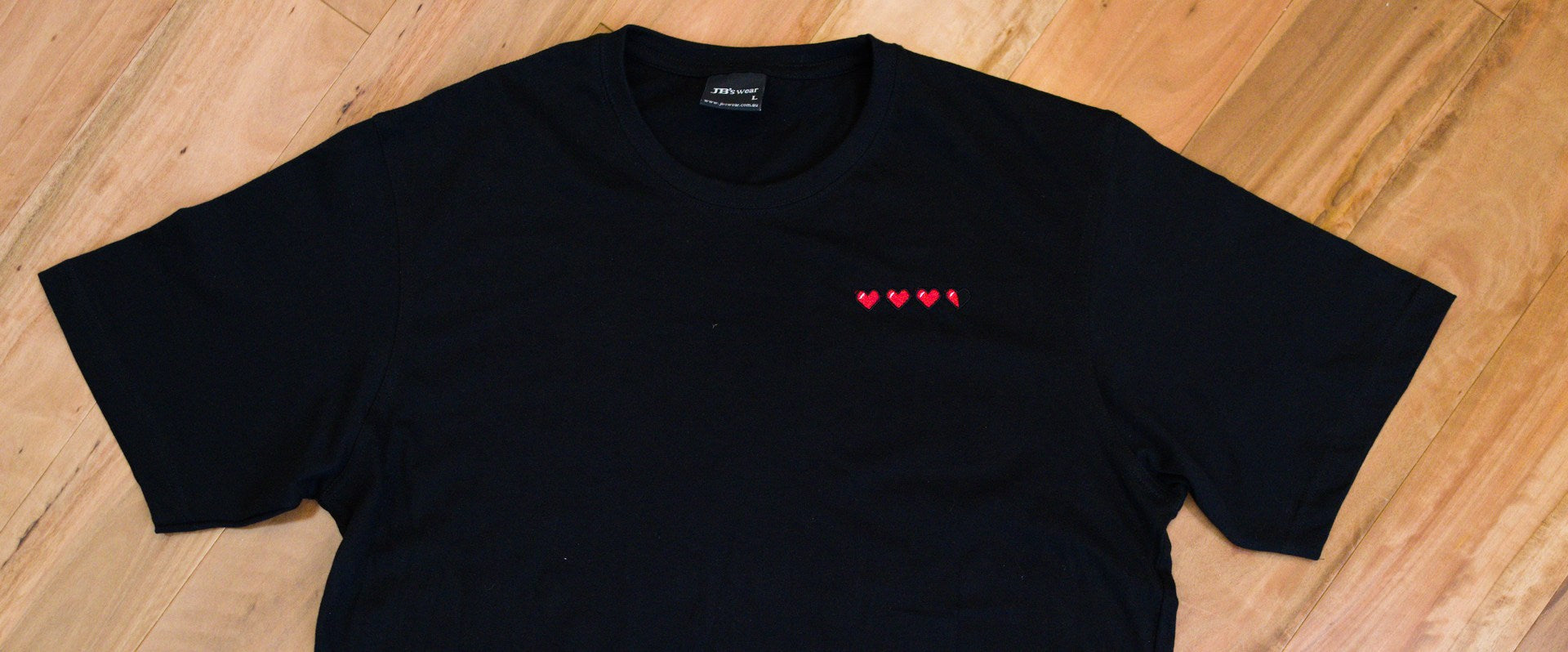 Close-up of 3.5 hearts pixel embroidery on a black t-shirt, Round Door Workshop Australia