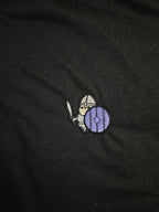 Detailed shot of an embroidered warrior holding their sword and shield up, ready to defend.
